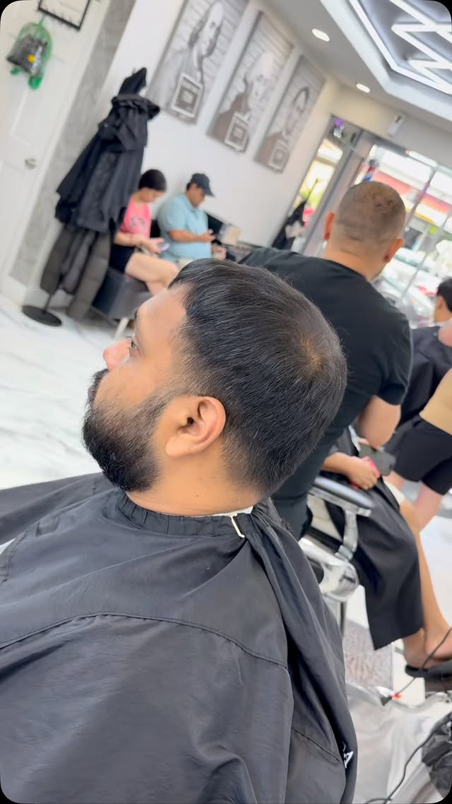Barber cutting hair inside Ampm Barbershop, Woodhaven